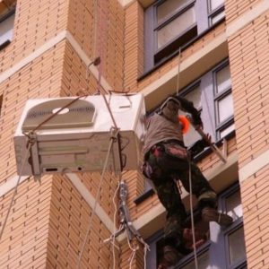 Τεχνικός με σχοινιά εγκαθιστά εξωτερική μονάδα σε πρόσοψη κτιρίου